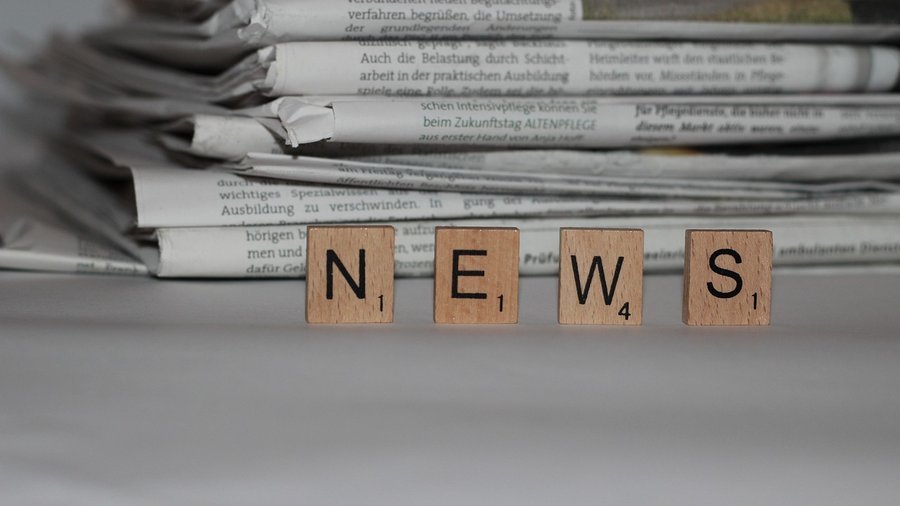Stapel von Zeitschriften vor denen die Scrabbel-Buchstaben "News" stehen.